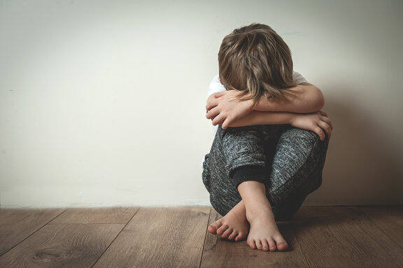 Kinderrechte_Shutterstock_772801951_Junge_sitzt_auf_Boden_bedeckt_Gesicht_c_Sharomka.jpg  